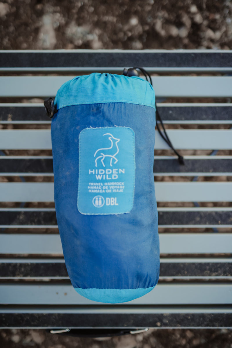A blue Hidden Wild double travel hammock, neatly packed in its stuff sack on a slatted surface. Ideal for any RV rental trip. — photo 9