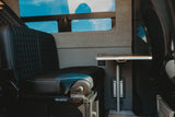 Comfortable RV rental interior with a black quilted bench seat and functional table, perfect for mobile living.