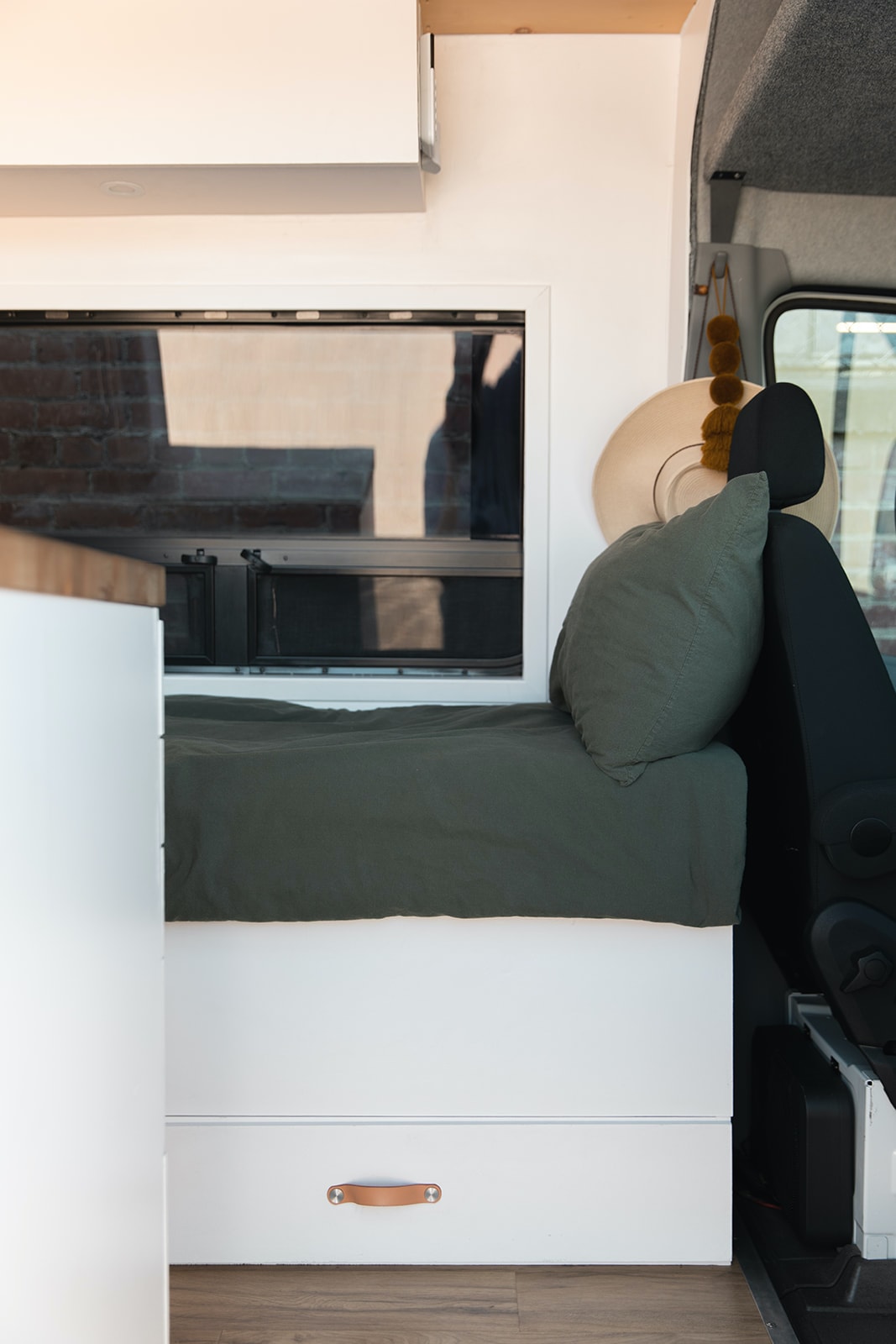  and a lounge with dining table.|Bright RV rental interior: Custom camper van with clean white cabinets — photo 7