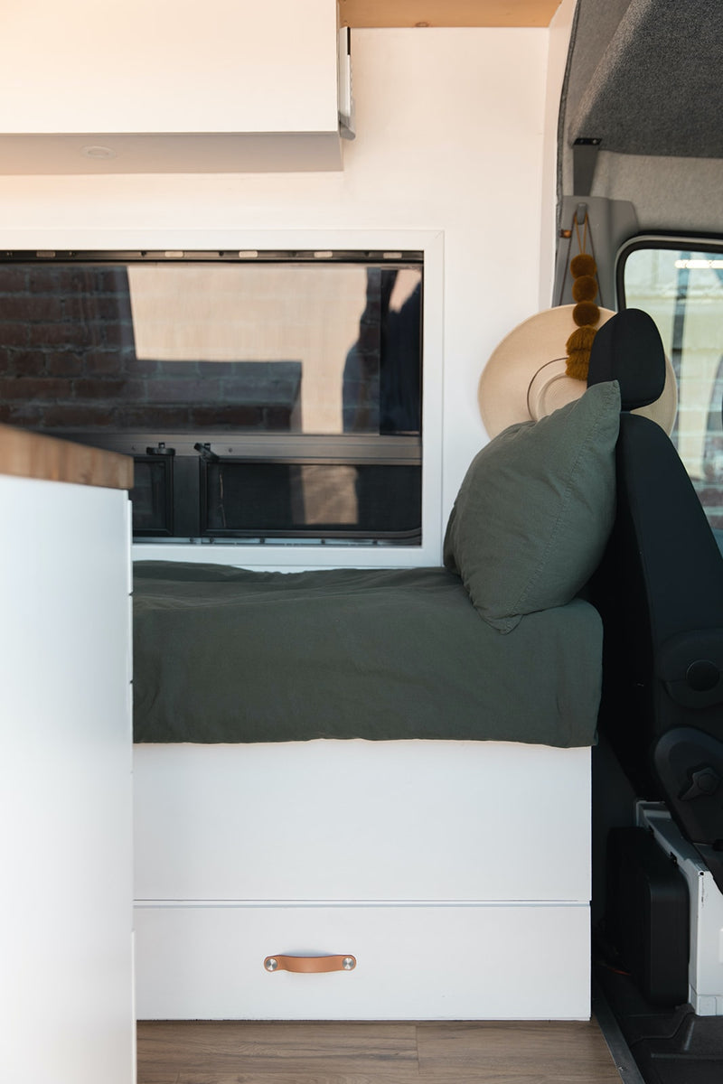  and a lounge with dining table.|Bright RV rental interior: Custom camper van with clean white cabinets — photo 7