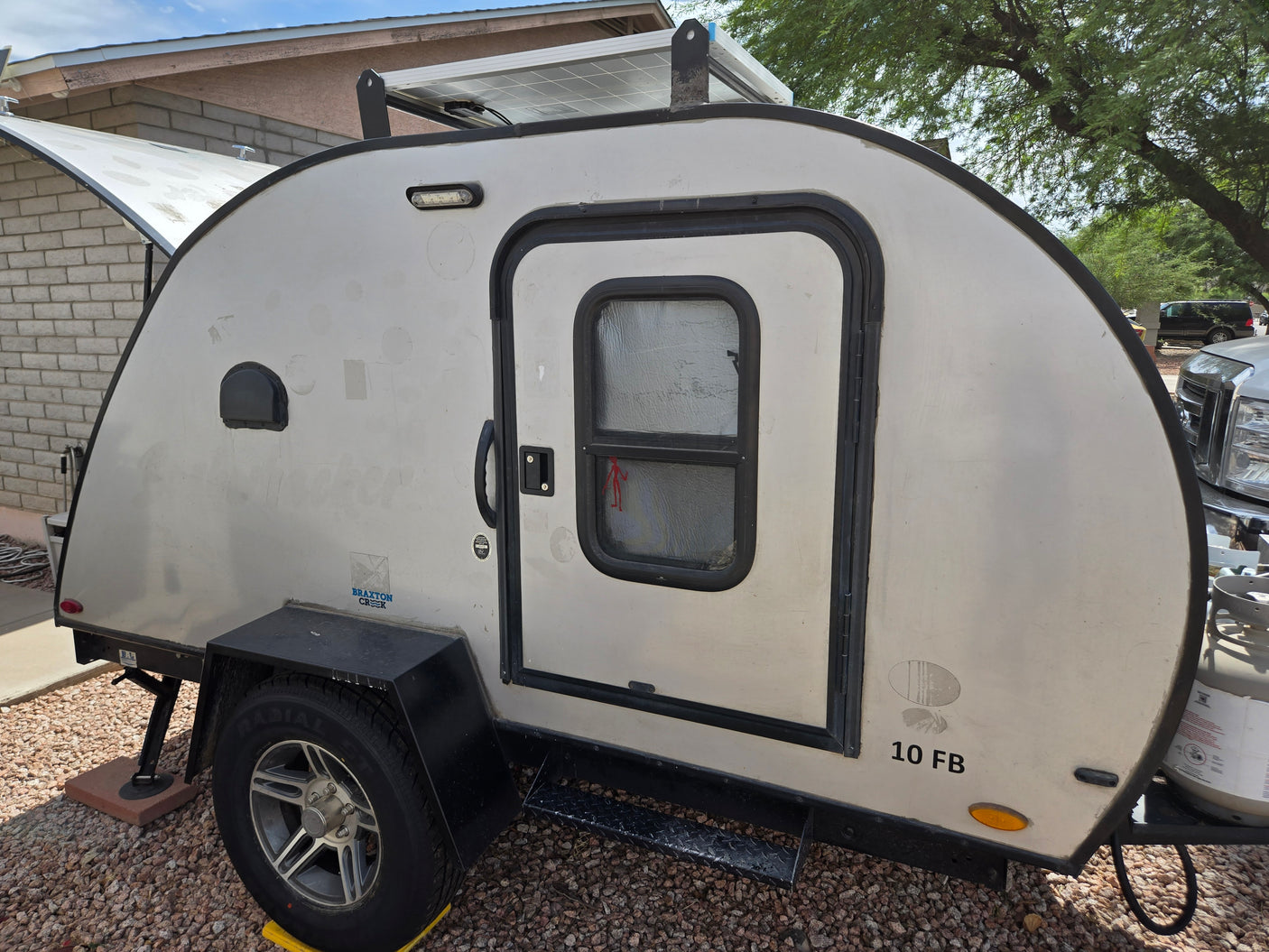 This Braxton Creek teardrop camper, with solar panel and propane tank, is perfect for your next RV rental adventure.