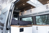 Cozy RV rental interior: Custom camper van features a modern kitchen, comfortable bed, and wood-paneled ceiling.