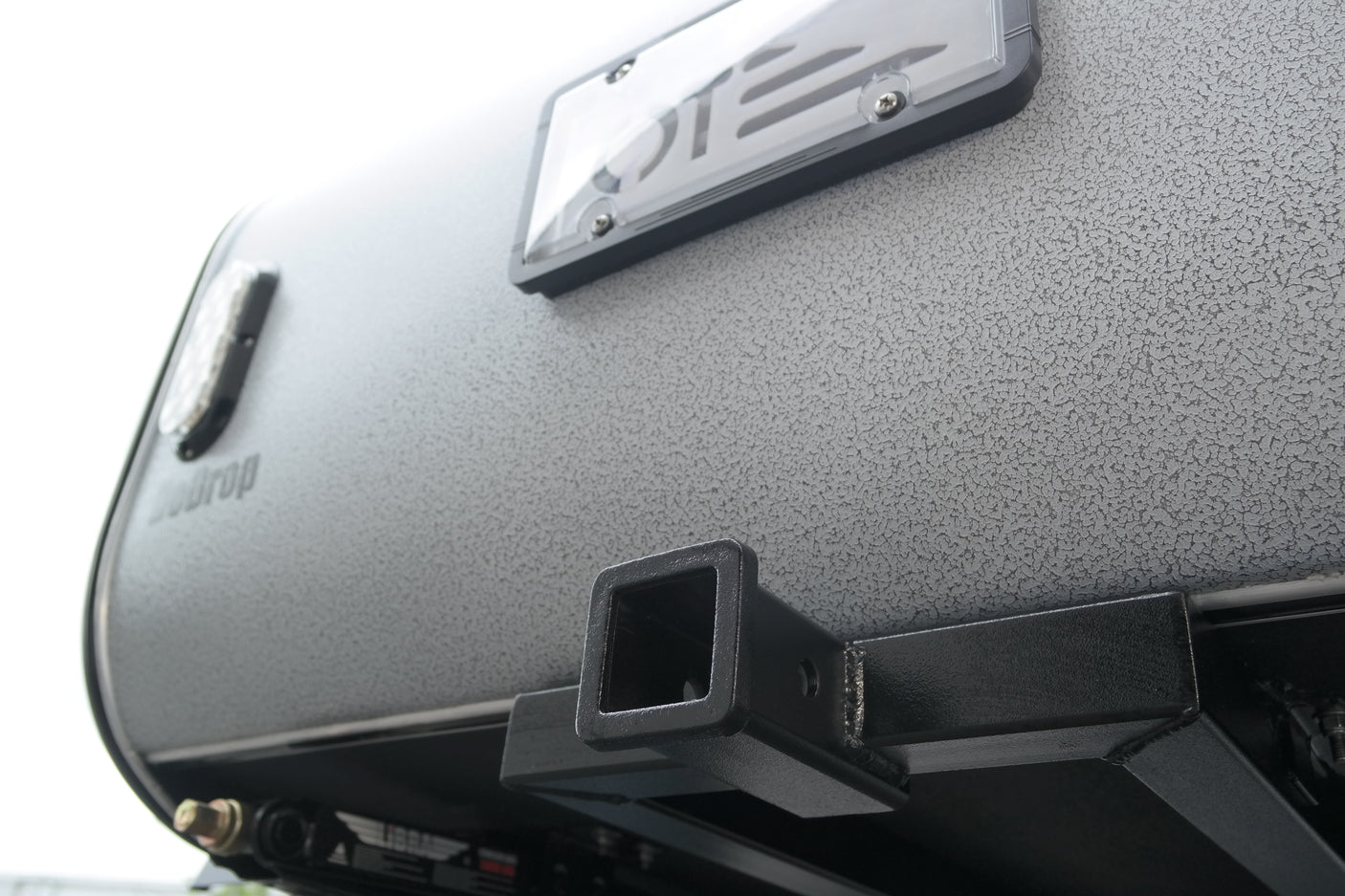 Textured grey Teardrop travel trailer rear, with license plate frame and hitch receiver for RV rental adventures.