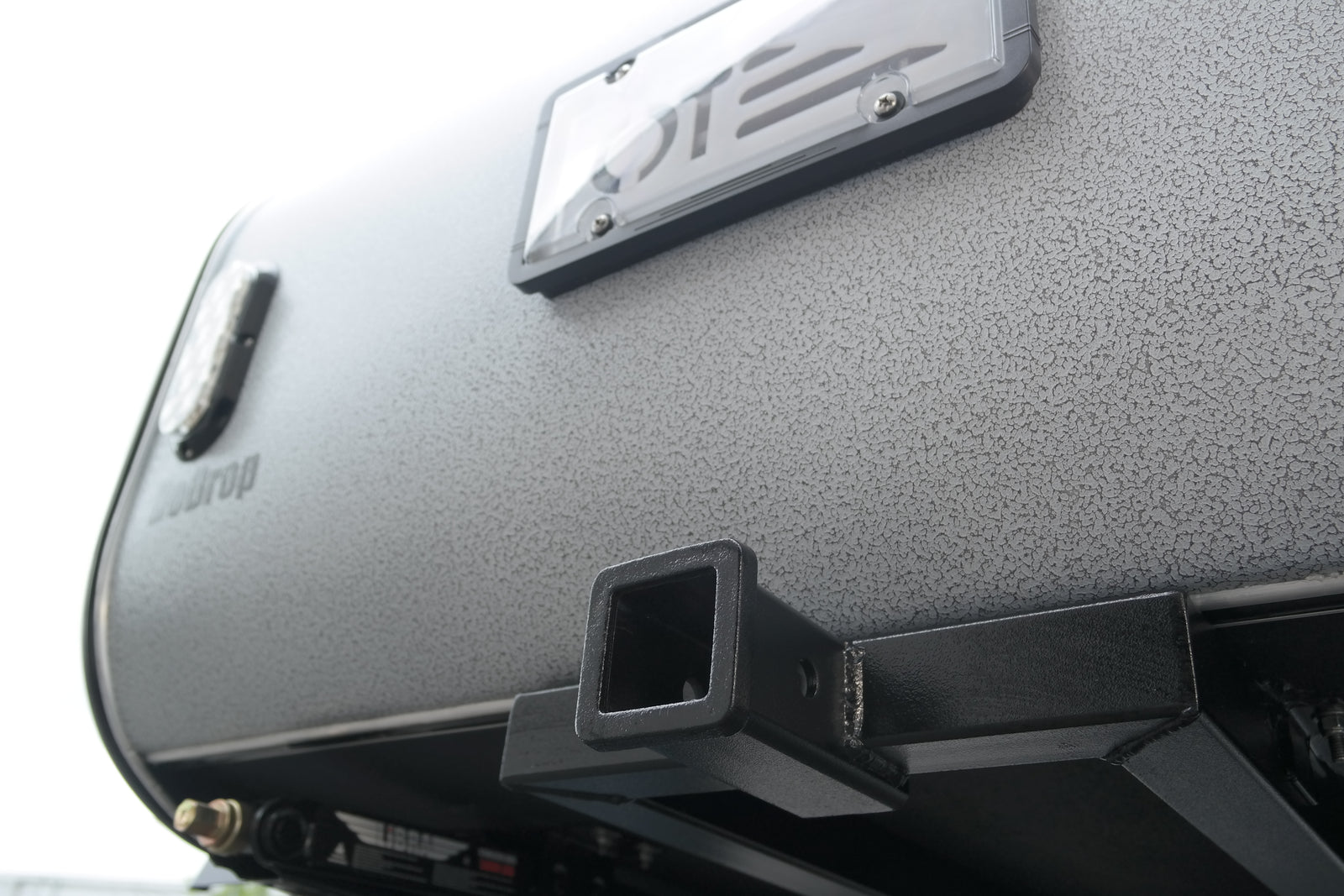 Textured grey Teardrop travel trailer rear, with license plate frame and hitch receiver for RV rental adventures.