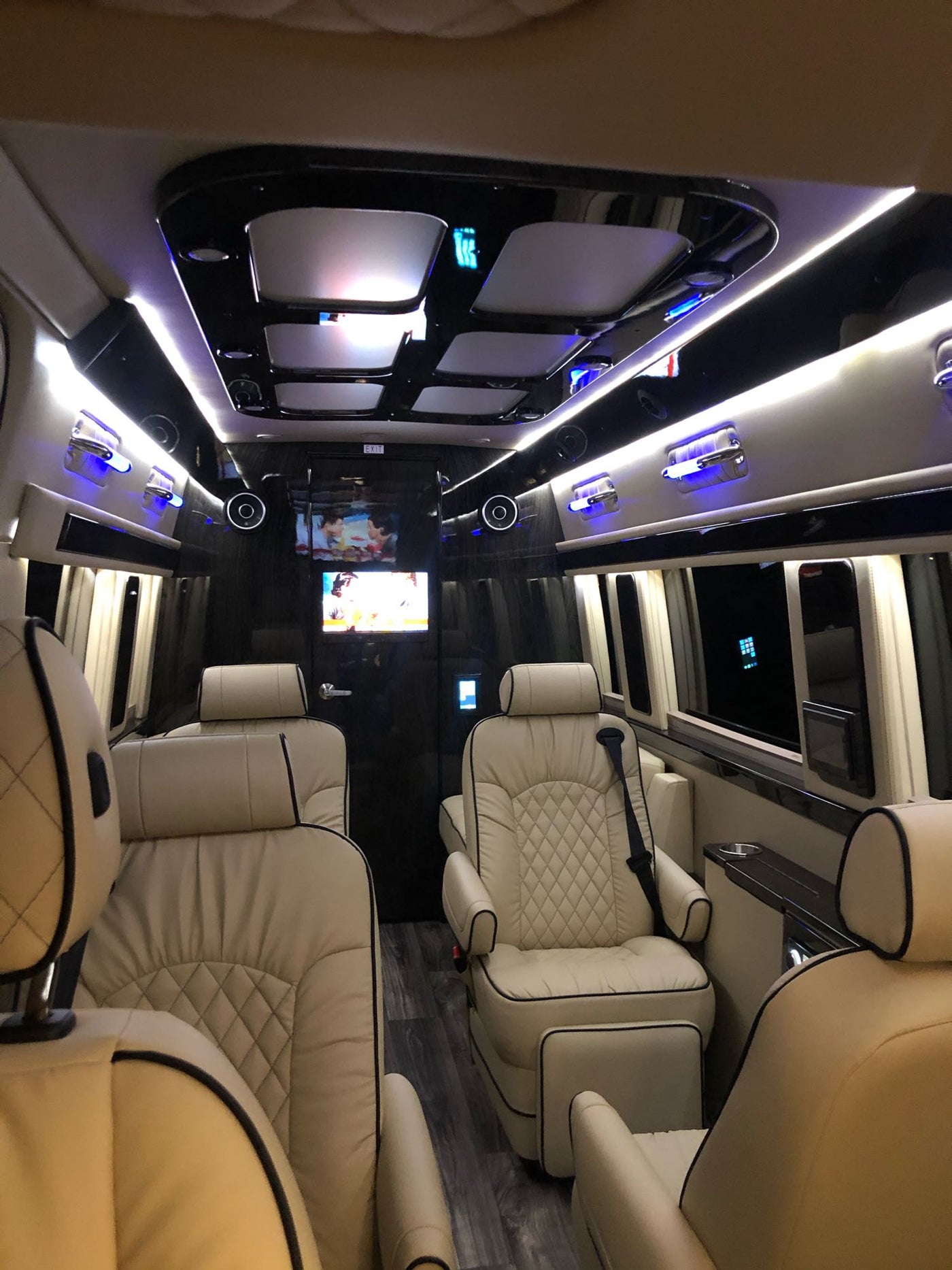 Step into this luxurious RV rental! Enjoy plush, diamond-stitched seating, multiple entertainment screens, and ambient blue lighting. — photo 12