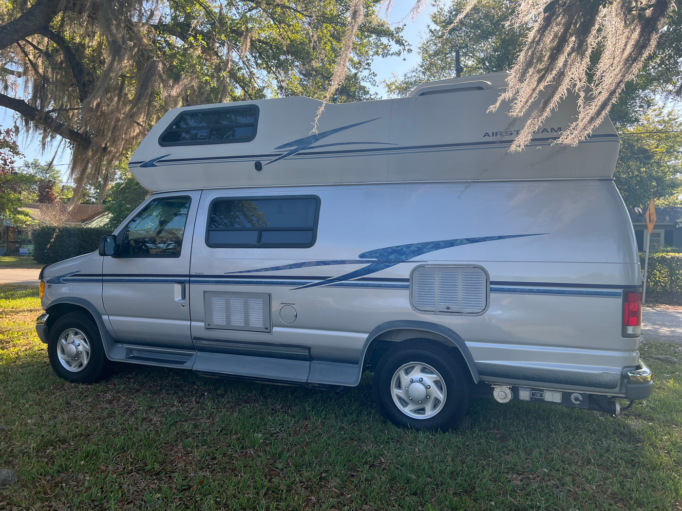 Silver Airstream camper van parked on grass under mossy trees, ideal for your next rv rental adventure. — photo 3