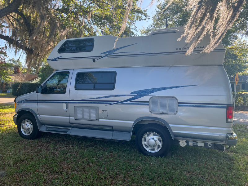 Silver Airstream camper van parked on grass under mossy trees, ideal for your next rv rental adventure. — photo 3