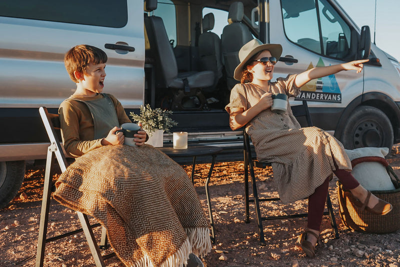  adults enjoy the van in a scenic outdoor setting.|Two happy children relax outside their RV rental van — photo 2
