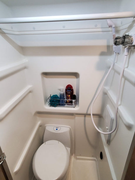 An RV rental's compact all-in-one bathroom unit, featuring a shower stall, toilet, and toiletries.
