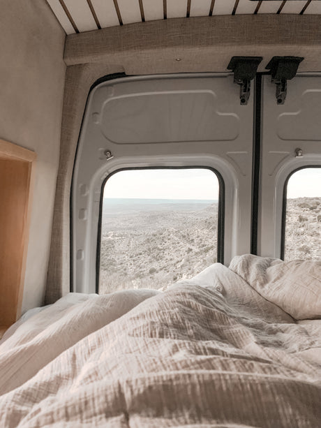Cozy RV rental bedroom with a stunning desert landscape view from the back windows, perfect for scenic travel.