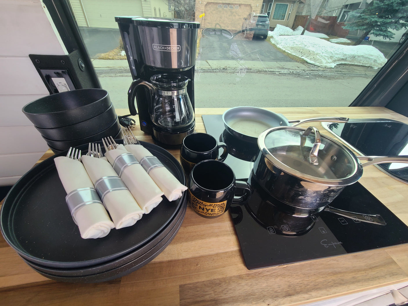 Equipped **rv rental** kitchen featuring a **coffee maker**, induction **cooktop**, **cookware**, & **dishes** for your travels.