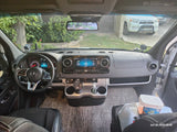 Inside a modern RV rental: Driver's cockpit of a Mercedes-Benz Sprinter van, showing dashboard, navigation, and RV essentials.