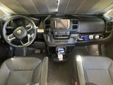Inside an RV rental van, the detailed dashboard includes a steering wheel, media screen, controls, and a pop-top caution sticker.