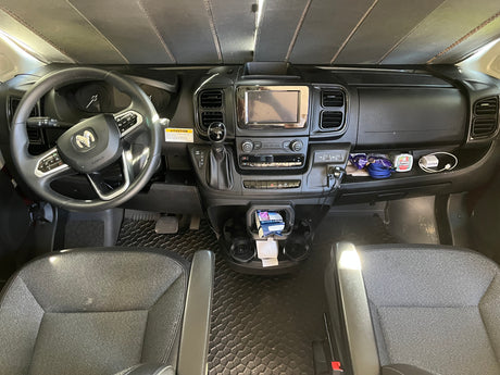 Inside an RV rental van, the detailed dashboard includes a steering wheel, media screen, controls, and a pop-top caution sticker.