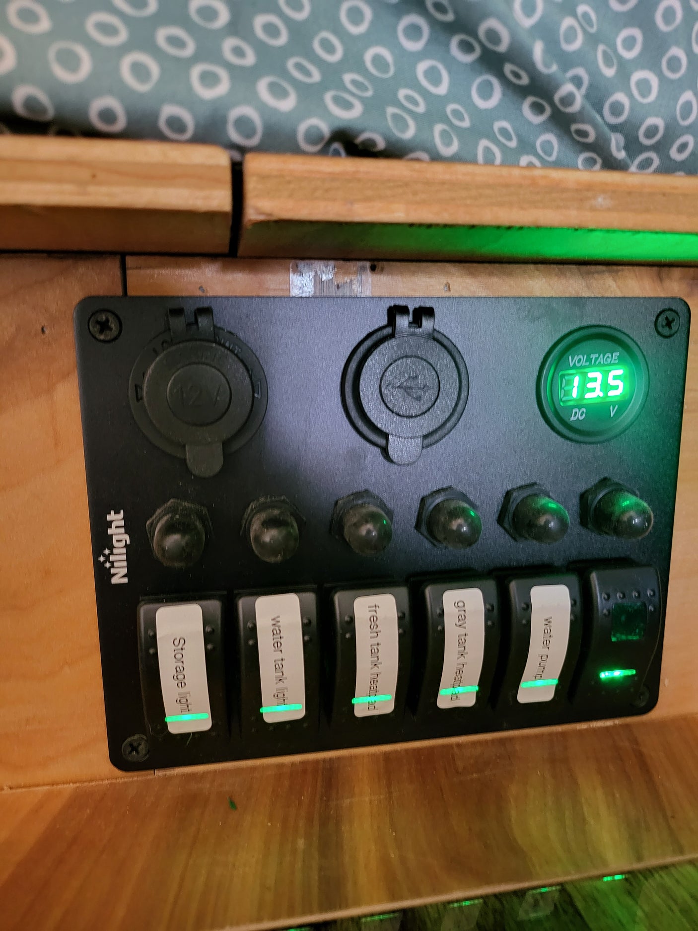 An RV rental electrical panel showing 13.5V and active switches for water pump, tank heaters, and lights.