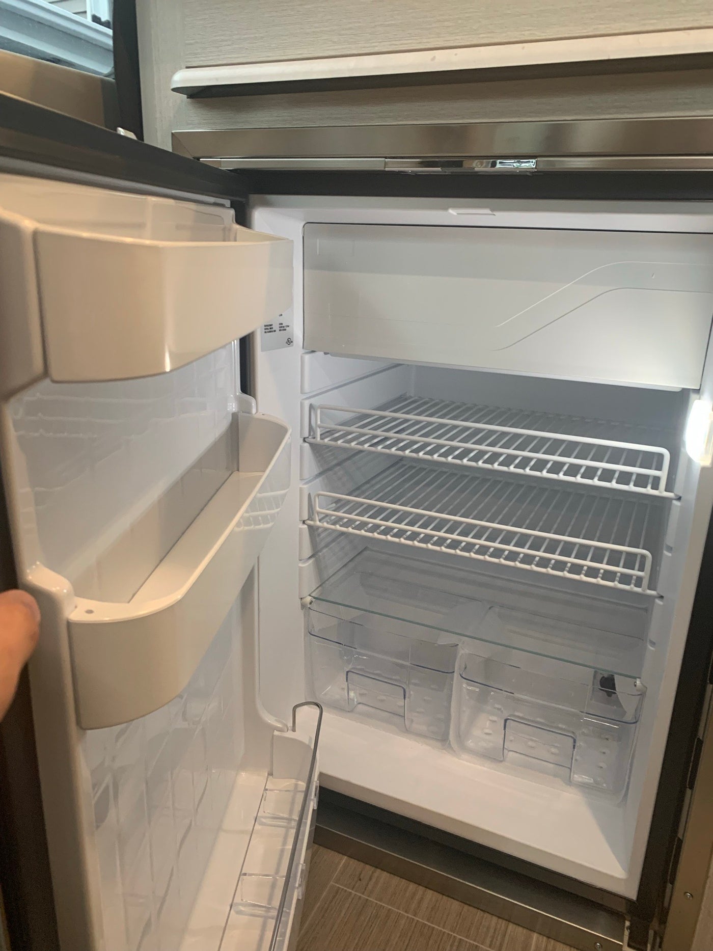 Open, empty refrigerator in an RV rental. Features white wire shelves, clear drawers, and door storage, ready for provisions. — photo 20