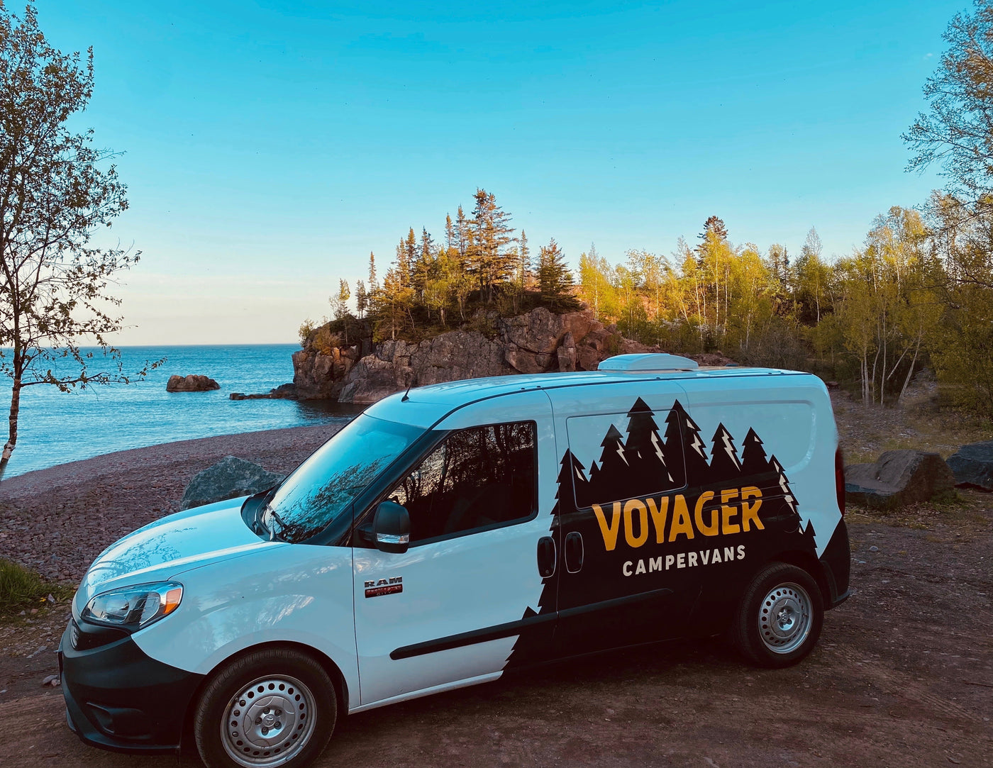 White and black Voyager campervan RV rental parked by scenic lake for outdoor adventures. — photo 14