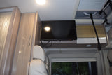 RV rental interior with a mounted TV, light wood cabinets, comfortable seating, and overhead storage.