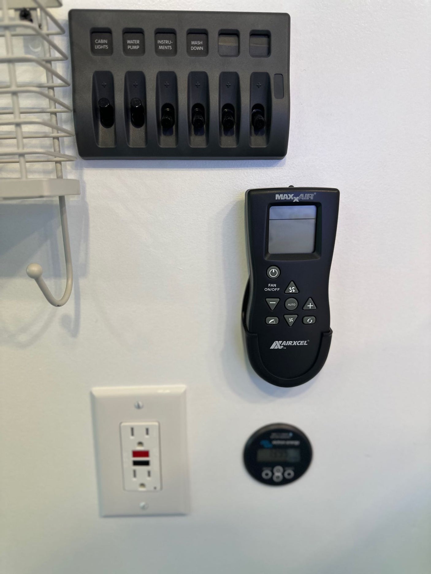 RV rental cabin with switches for lights/water, Maxxair AC remote, GFCI outlet, and utility meter. Essential RV controls.