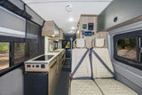 RV rental interior showcases a compact kitchen with sink and stovetop, comfortable seating, and overhead storage for road trips.
