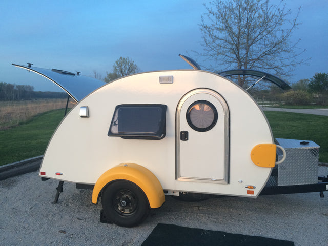 Compact white teardrop trailer, perfect for your next rv rental adventure. Features yellow fenders, an open rear hatch, and storage box.
