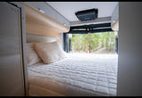 Cozy RV rental bedroom with a comfy bed and a beautiful forest view through the open rear doors.
