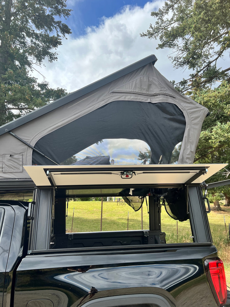 This rv rental showcases a black pickup truck with a deployed gray rooftop tent and open truck bed storage. Ideal for camping. — photo 16