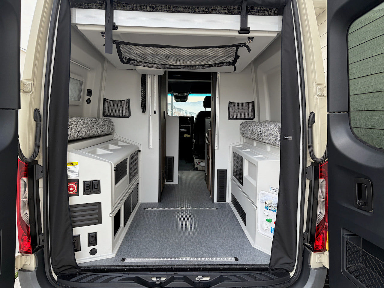 Open rear doors reveal a functional rv rental camper van interior with flexible seating and storage. — photo 3