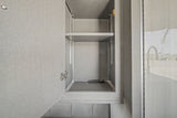Inside an RV rental: an open grey cabinet with adjustable shelves and a remote control, perfect for organized travel storage.