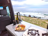 Cozy RV rental interior with an ocean view, charcuterie, wine, and a compact kitchen.
