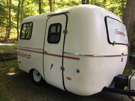 Charming Scamp travel trailer in a wooded setting, ideal for an RV rental adventure and a cozy camping experience.