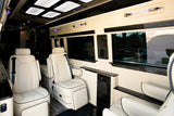 Plush interior of a luxury RV rental, featuring custom leather seating, ambient lighting, and wood accents.