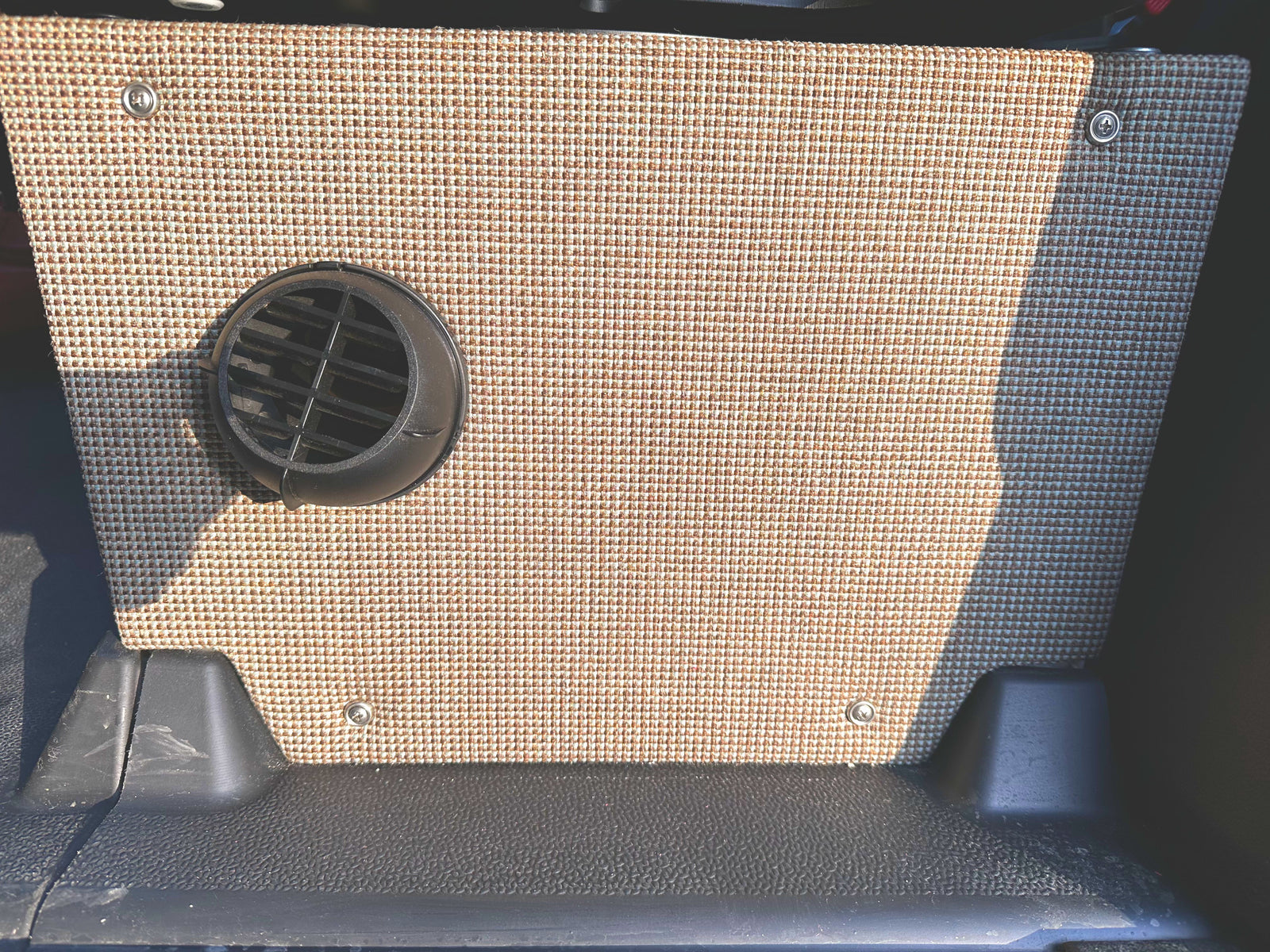 RV rental camper van interior. Beige woven fabric panel with black circular vent & durable floor.