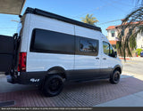 Explore more with this rugged white Sprinter-style RV rental, ready for adventure with off-road tires and a roof awning.