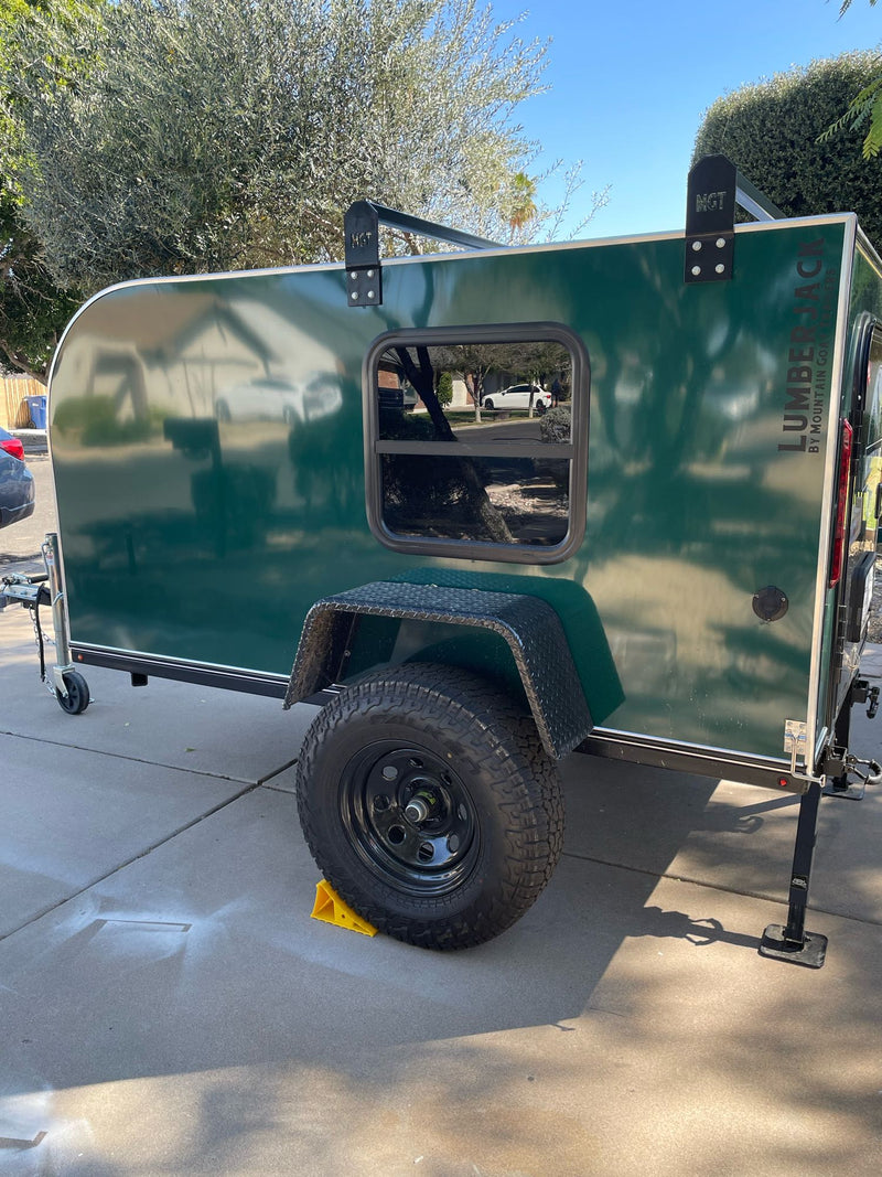  ready for adventure.|Cozy green teardrop RV rental ready for adventure. Open door reveals comfy bed with plaid blanket. Perfect for camping.|This dark green teardrop camping trailer — photo 7