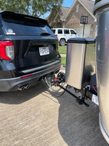 Black SUV towing a silver RV rental, securely connected by hitch & chains for recreational travel. Texas plate visible.