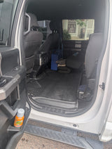 Rear interior of a large vehicle, showing flexible cargo space, floor mats, blue container, and blankets. Great for an RV rental.