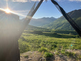 Greet the day from your RV rental! A sun-drenched mountain valley through a mesh window. Perfect nature escape.