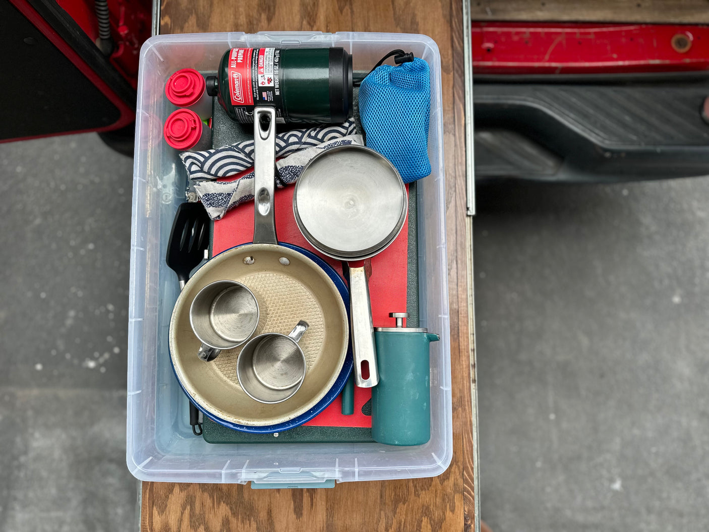 RV rental camping kitchen essentials, including propane, cookware, and coffee maker, stored compactly in a clear bin.