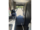 RV rental: Inside a camper van, showing the galley kitchen with sink and open rear view to a street.
