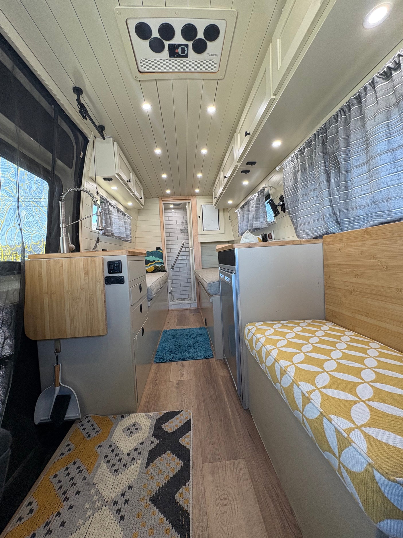 A modern rv rental interior features a compact kitchen, shower, comfy seating, and ample storage for travel adventures.