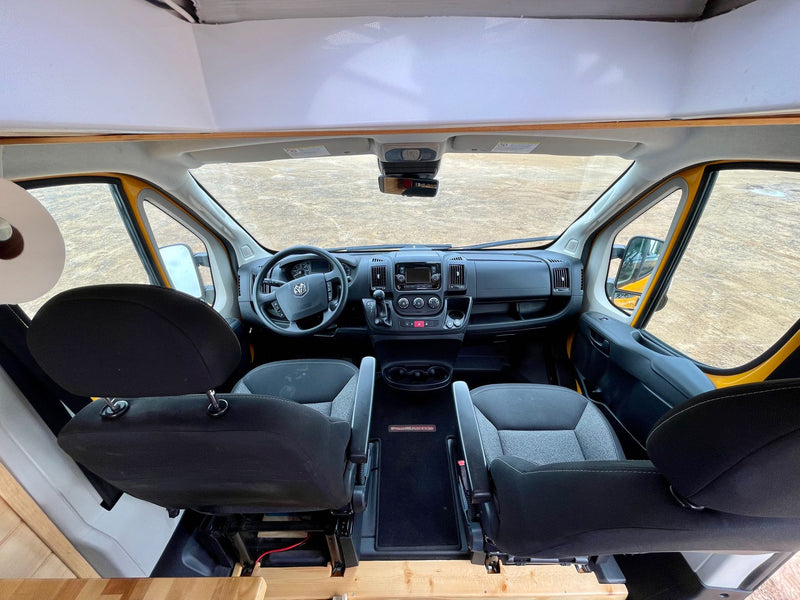  and a comfy bed. Perfect for mobile living.|RV rental interior: Pull-out refrigerator visible under custom blue cabinets next to a comfy bed.|RV rental interior: cozy wood plank ceiling — photo 8