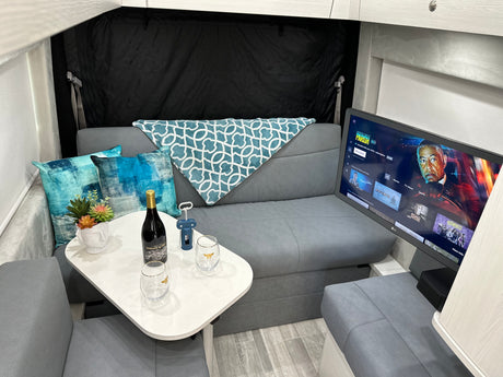 RV rental interior featuring a cozy lounge area with TV, wine, and comfortable seating, ideal for relaxation.