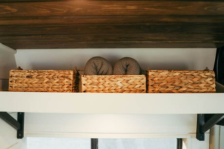 Wicker baskets with rolled towels on a shelf provide smart storage for your RV rental experience.