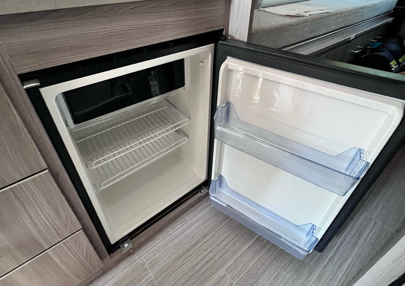 Inside an RV rental: A compact, open mini-fridge. White interior with wire shelves and clear plastic door bins. — photo 12