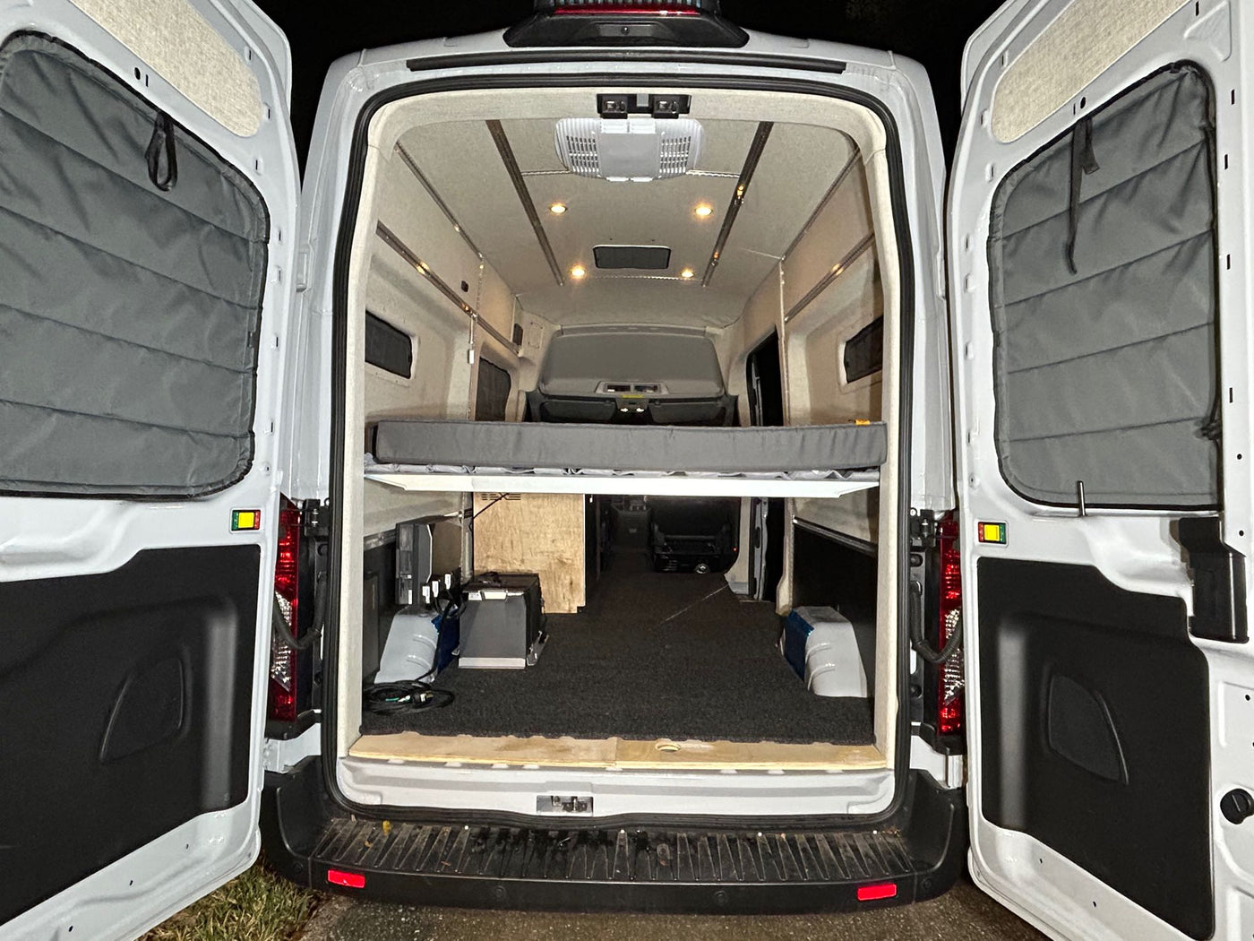  perfect for an RV rental or road trip adventures.|Rear view into a well-lit RV rental camper van interior. Features a comfy bed platform — photo 3