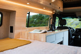 Cozy RV rental interior: compact kitchen, comfortable bed, and scenic window for travel.