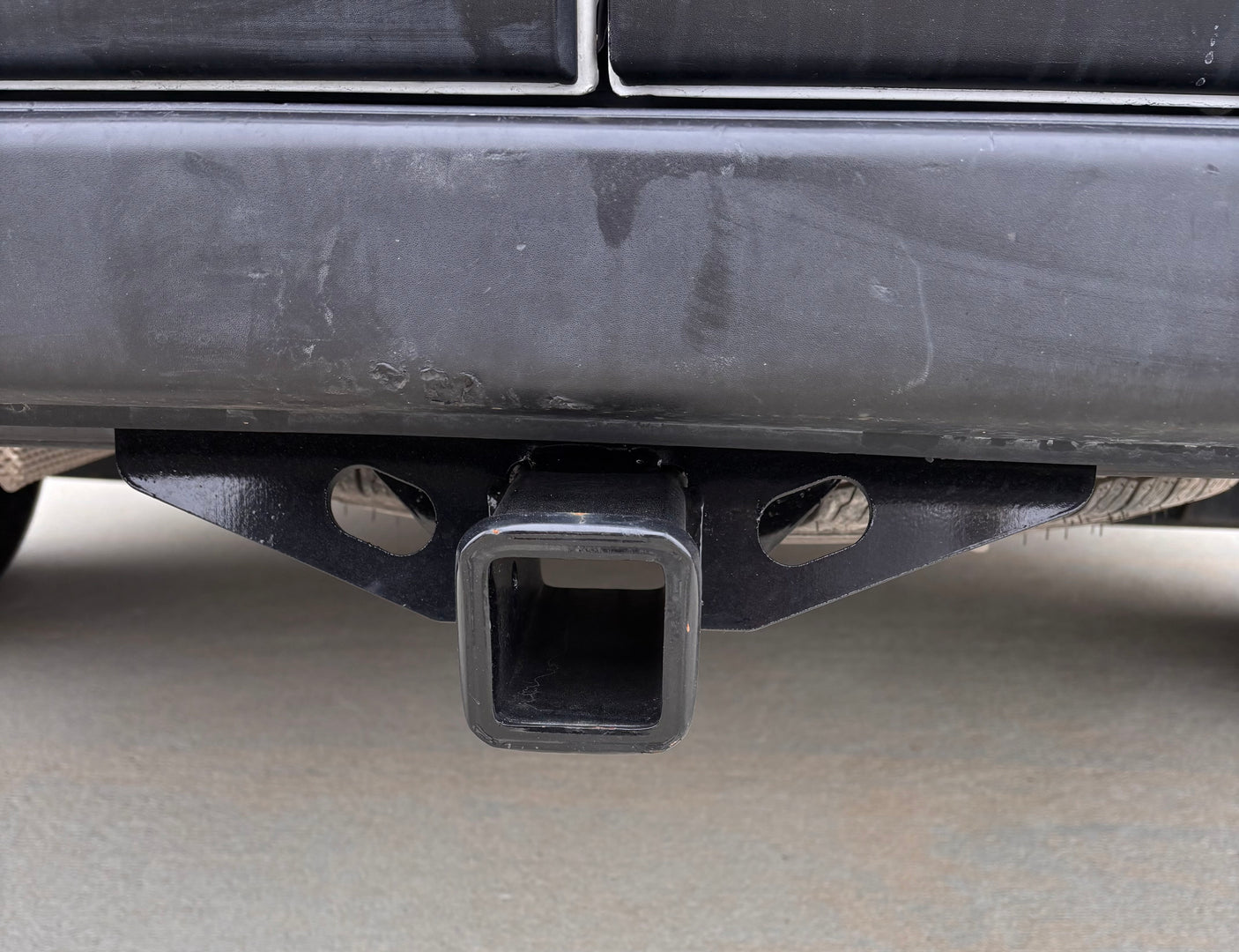 Close-up of an RV rental vehicle's rear bumper and heavy-duty black towing hitch receiver, ready for trailer hook-up.