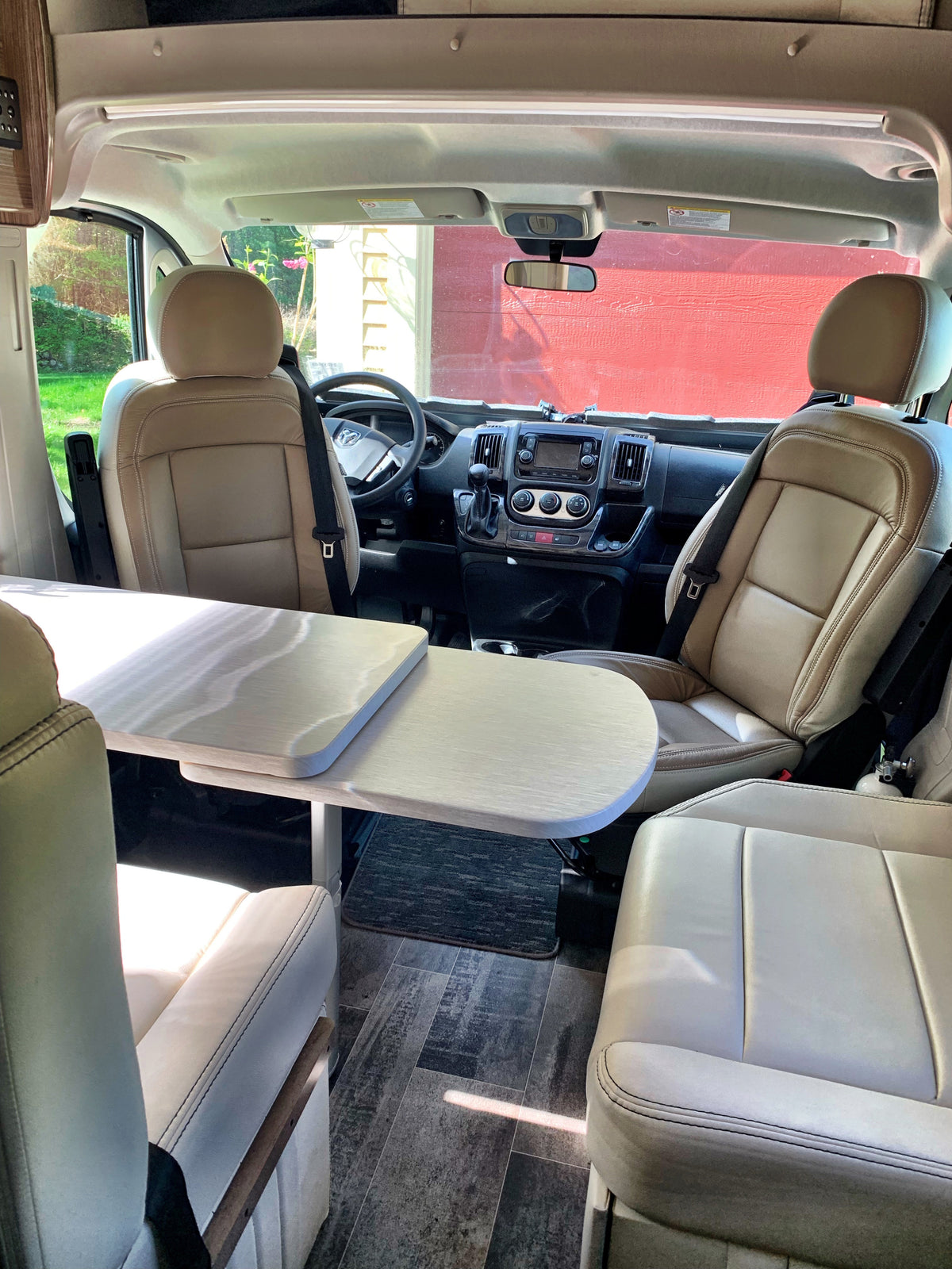 Spacious RV rental interior featuring tan seats, a central table, and a clear view of the front cab and dashboard. — photo 11