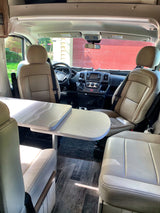 Spacious RV rental interior featuring tan seats, a central table, and a clear view of the front cab and dashboard.